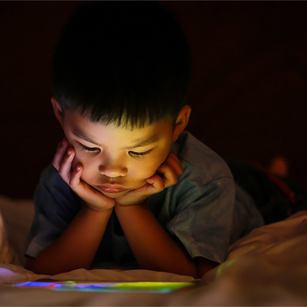 Toddler looking at iPad in bed